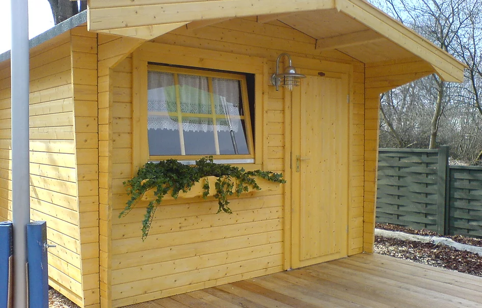 Holz Gartenhaus mit Satteldach und überdachtem Eingang. Außenleuchte neben Eingangstür