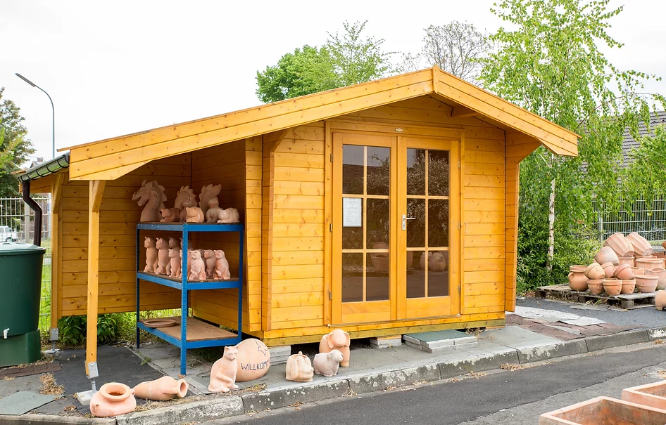 Holz Gartenhaus mit Satteldach, links verlängert für überdachten Unterstand. Verglaste Doppeltür an der Front