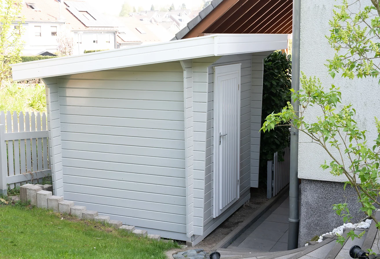 Gerätehaus aus Holz, grau lackiert, mit Pultdach. Seitenansicht