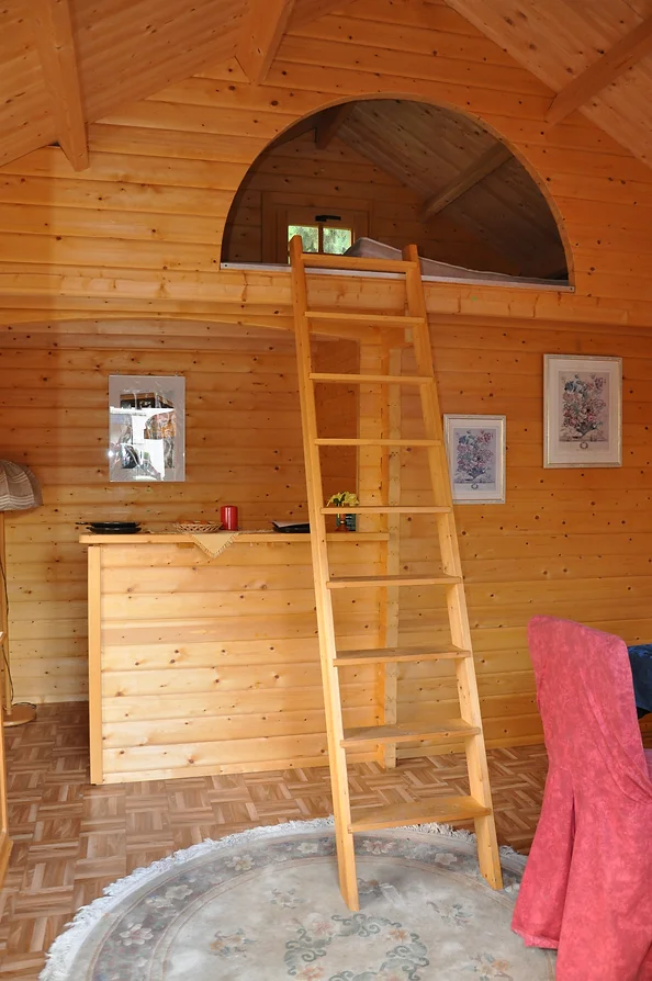 Innenansicht Holz Gartenhaus. 2 Geschosse. Leiter, die zum Schlafbereich oben führt. Unten: Tresen aus Holz